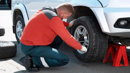 Mechanic checking and tightening the wheel of a car during roadside tyre repair